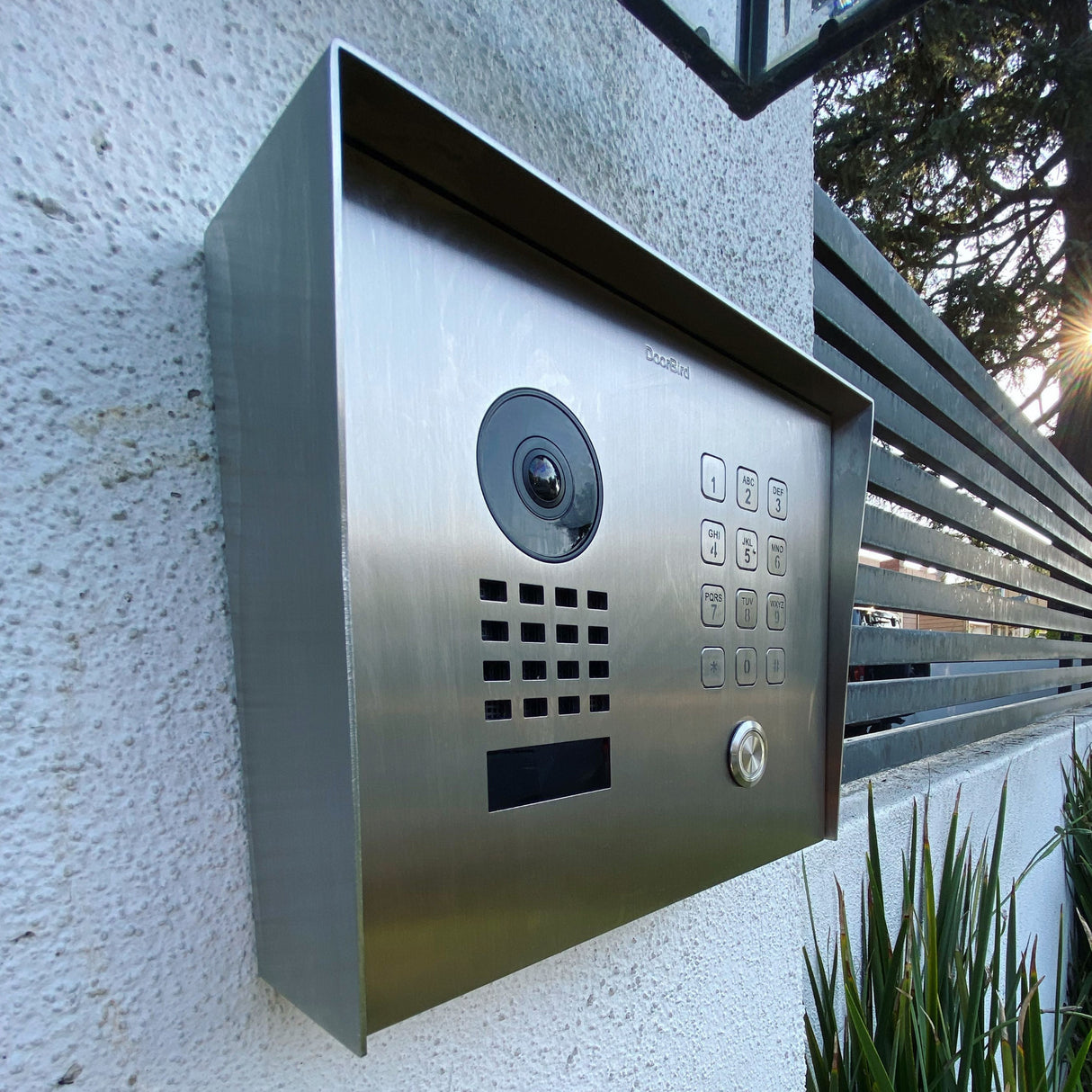 DoorBird D1101KH Smart Intercom System shown on a wall next to a pedestrian gate